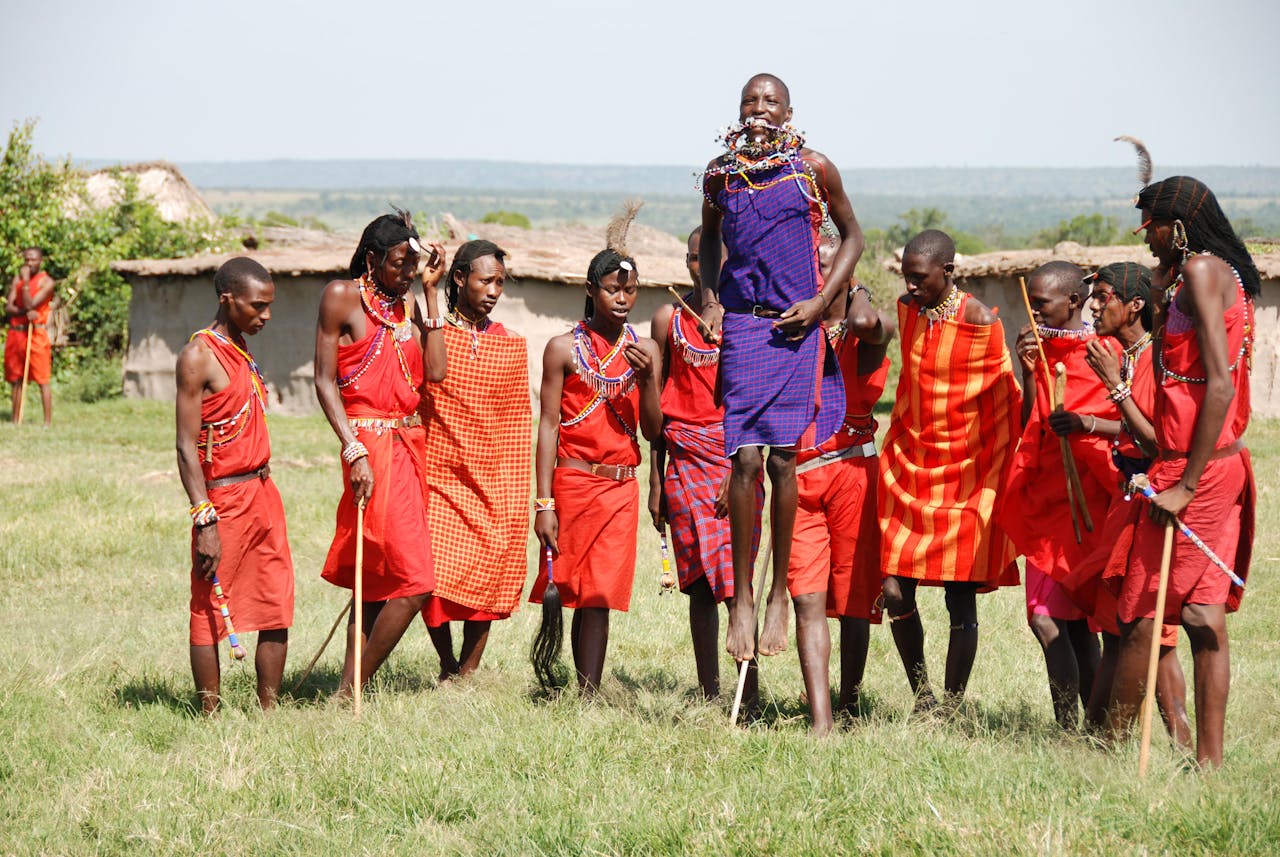 Group of Maasai people in traditional attire performing a vibrant dance ceremony outdoors.